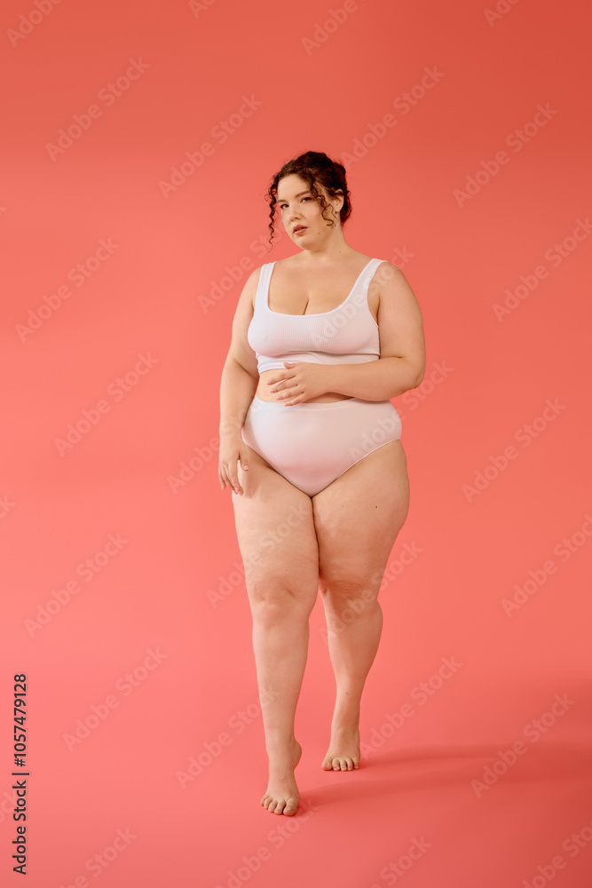 A confident plus size woman showcases her beauty in a pastel pink outfit, posing with grace. A confident plus size woman showcases her beauty in a pastel pink outfit, posing with grace.
