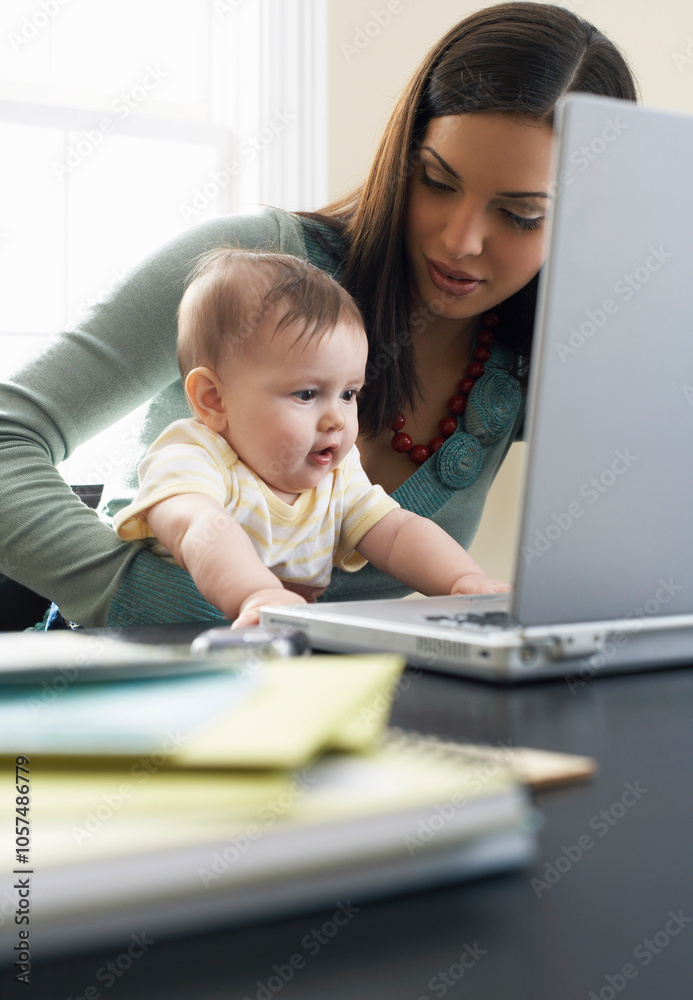 Mother Using Laptop Computer With Baby on Her Lap Mother Using Laptop Computer With Baby on Her Lap