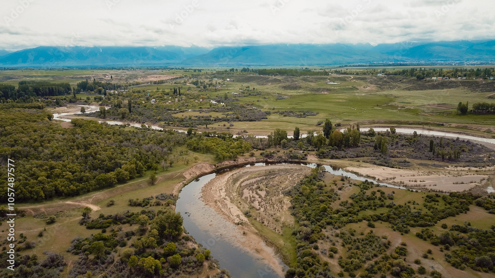 Aerial view of lush landscape and winding river in rural Kyrgyzstan during daylight Aerial view of lush landscape and winding river in rural Kyrgyzstan during daylight