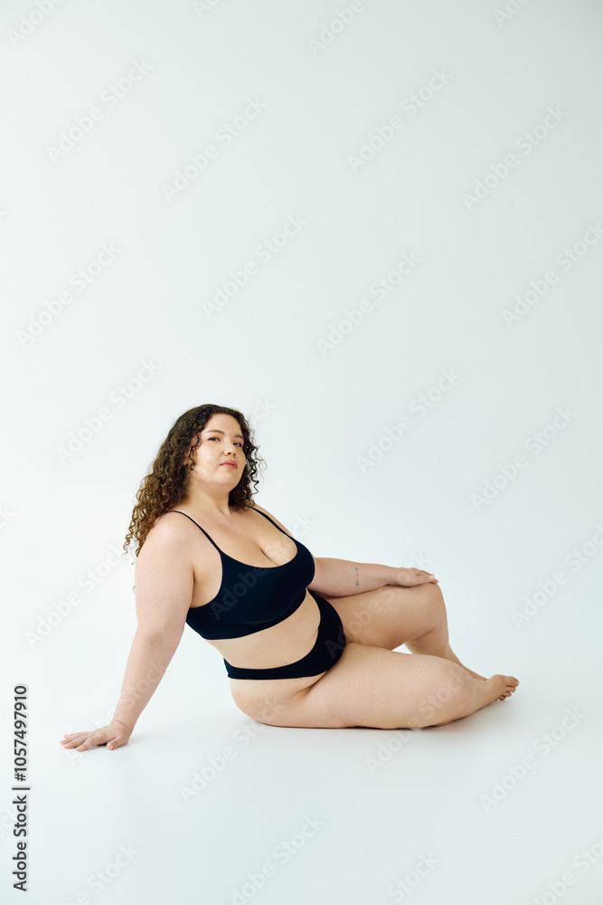 A plus size woman exudes confidence while posing elegantly against a simple backdrop. A plus size woman exudes confidence while posing elegantly against a simple backdrop.