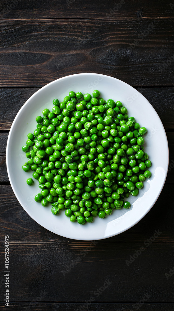 Fresh and delicious green peas fill a white plate resting on a dark wooden table Fresh and delicious green peas fill a white plate resting on a dark wooden table