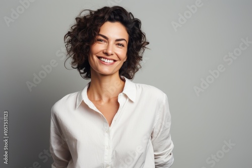 Portrait of a satisfied woman in her 40s wearing a simple cotton shirt on blank studio backdrop