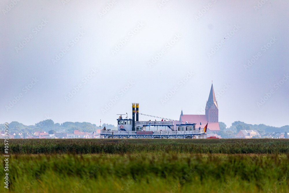 Obraz premium Raddampfer auf dem Bodden hinter dem Deich mit Barth im Hintergrund.