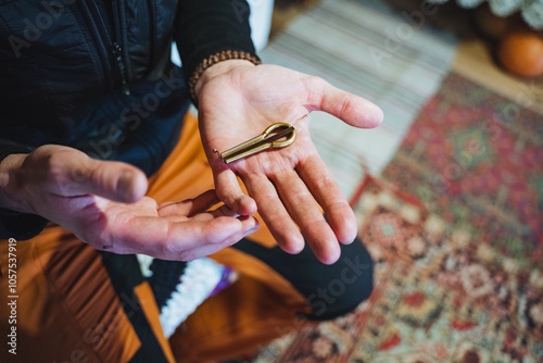 A brass jew's harp lies on the palm of your hand, a demonstration of the folk instrument kubyz, male hands hold a jew's harp.