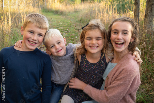 Close-up portrait of four siblings with arms around each other smiling at the camera in a rural setting in Beckwith Township at Carleton Place in the Ottawa Valley; Ontario, Canada photo