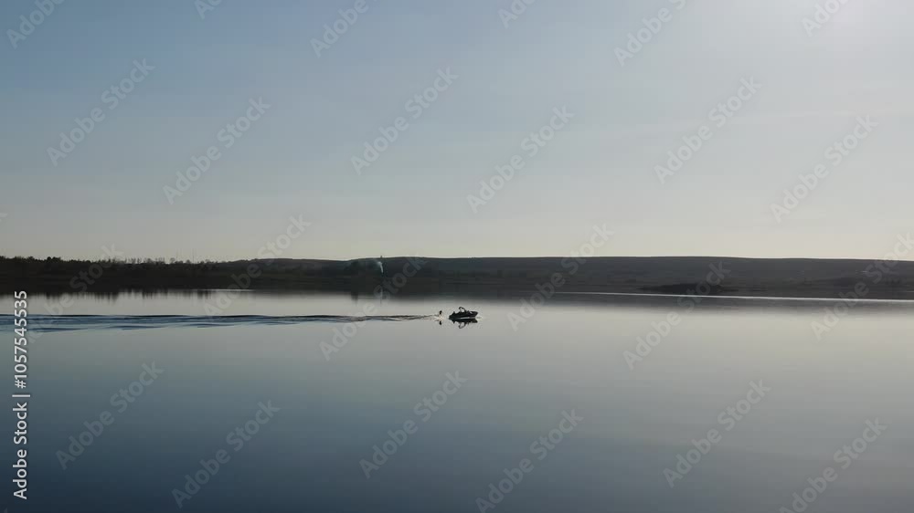 A boat rides on a lake with a wakesurf rider A boat rides on a lake with a wakesurf rider