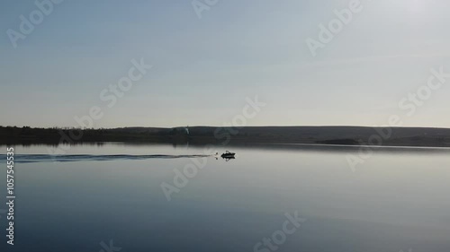A boat rides on a lake with a wakesurf rider