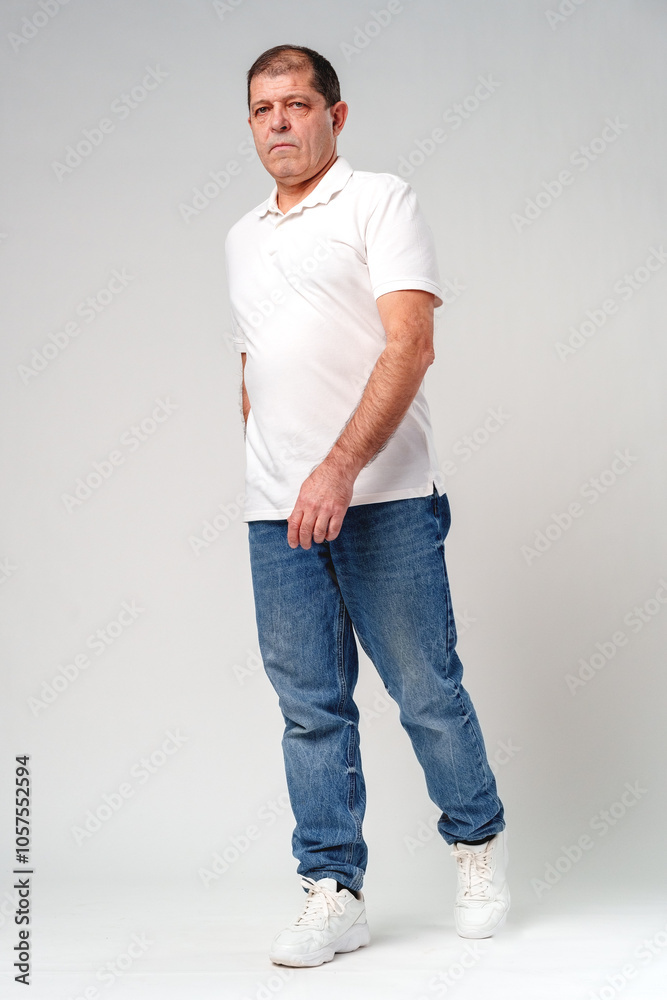 A middle-aged man poses confidently in casual attire against a neutral background A middle-aged man poses confidently in casual attire against a neutral background