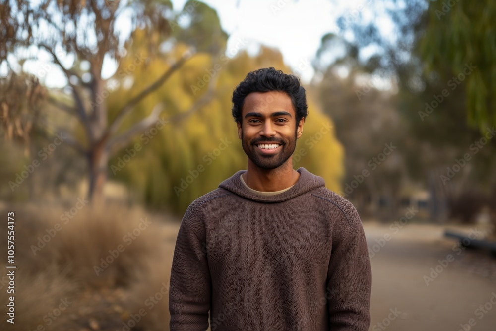 Portrait of a satisfied indian man in his 20s wearing a cozy sweater in empty modern loft background Portrait of a satisfied indian man in his 20s wearing a cozy sweater in empty modern loft background
