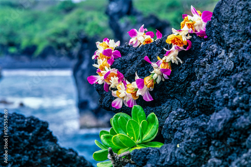 Flower lei on lava rock with ocean background, Hawaii, USA; Hawaii, United States of America