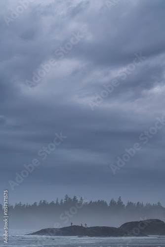 People exploring the rocks that are along Long Beach, just outside of Tofino on Vancouver Island.  Moody conditions exist as a storm quickly approaches; Tofino, British Columbia, Canada photo