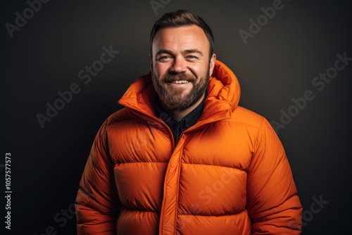 Portrait of a smiling man in his 30s donning a durable down jacket in plain cyclorama studio wall