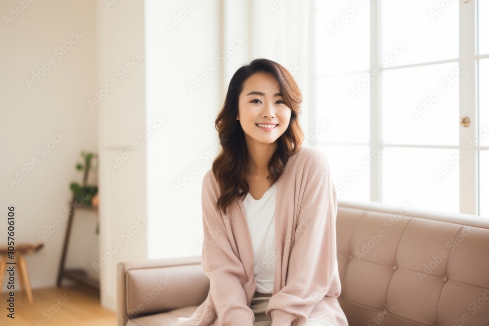 Portrait of a satisfied asian woman in her 20s wearing a chic cardigan on crisp minimalistic living room Portrait of a satisfied asian woman in her 20s wearing a chic cardigan on crisp minimalistic living room