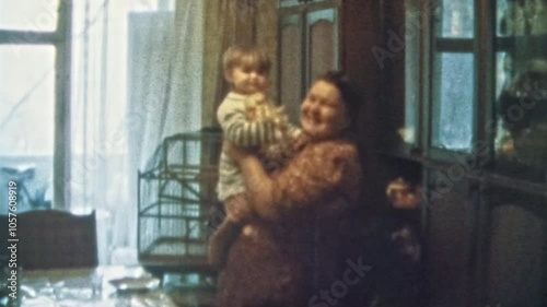 Happy grandmother holding granddaughter in arms in room indoors. Smiling granny proud of heiress child. Cheerful senior woman portrait. Vintage color film. Family happiness archive. Retro 1980s. 4k