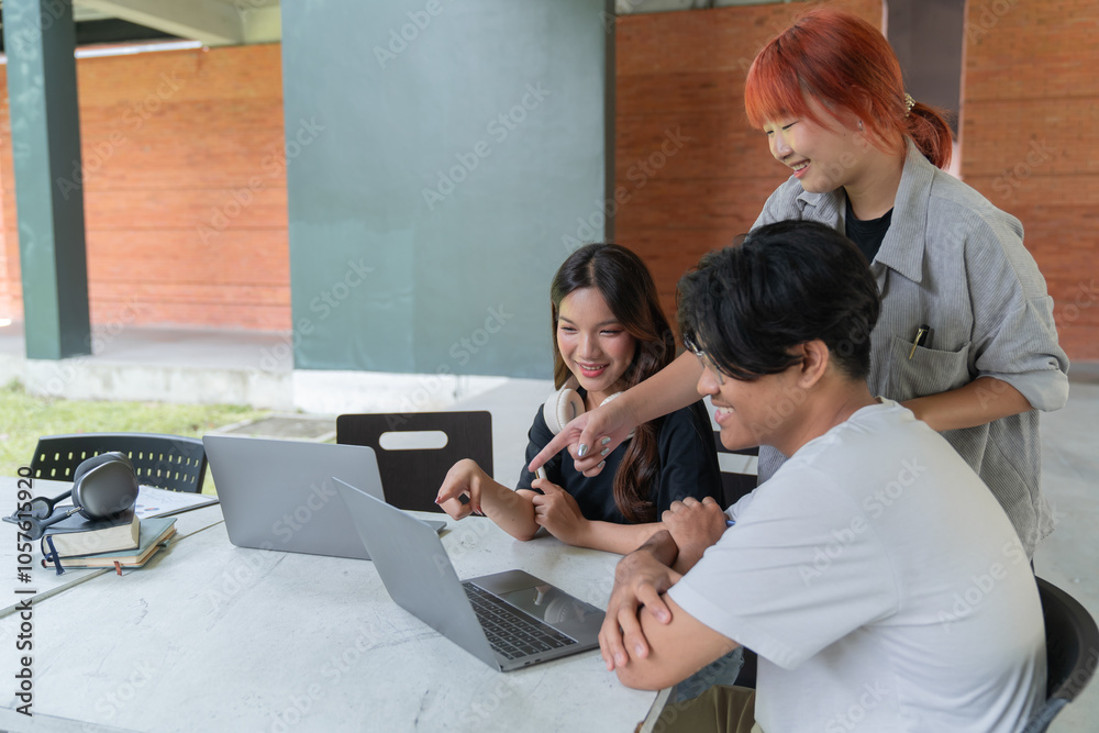 Obraz premium Three young university students are working together on a project, pointing at a laptop screen and discussing ideas in a collaborative and engaging manner