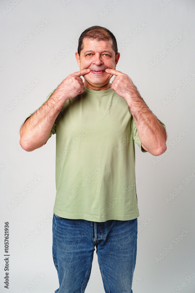 An older man smiling while making a funny face in a neutral studio background An older man smiling while making a funny face in a neutral studio background