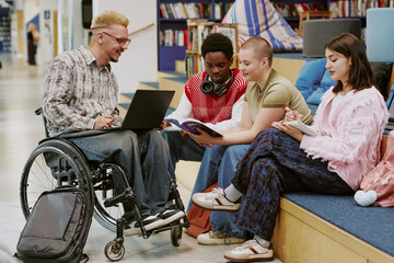 Group of diverse young individuals engaging with technology and books in contemporary library. Inclusive setting highlighting collaboration and learning