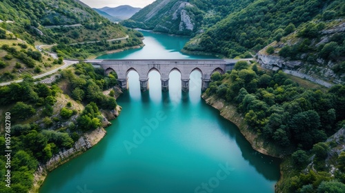 The lake water is blue-green, surrounded by green mountains and forests on both sides of the river, with an ancient stone arch bridge across it