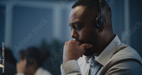 Modern call center office of mental health line: Close up portrait of African American hotline specialist in headset sitting at computer, listening person, providing online psychological assistance.