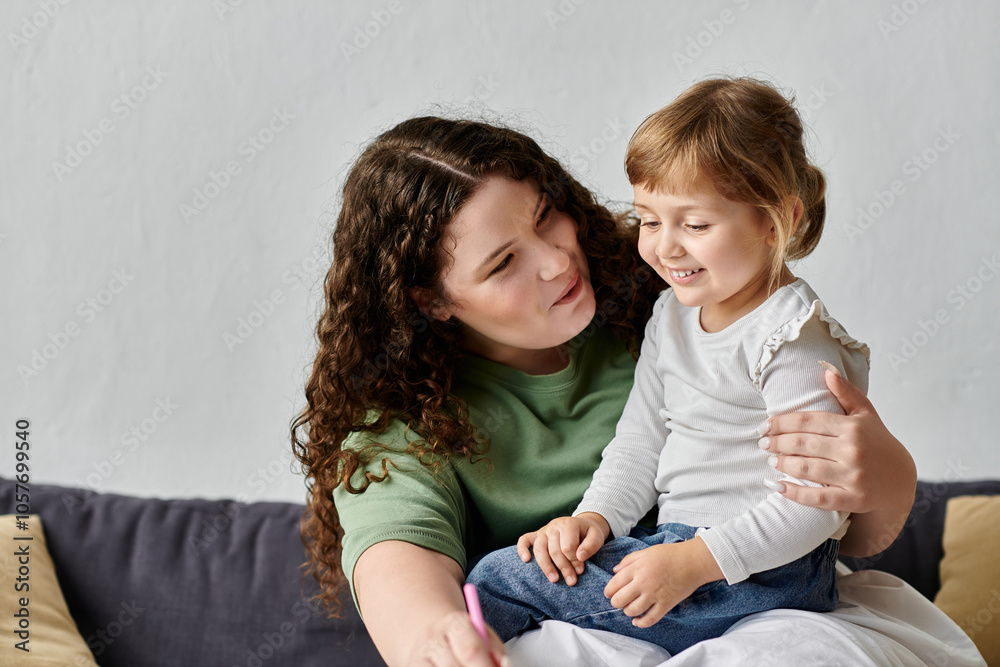 A loving mother engages with her daughter, sharing smiles and creativity in a cozy living space. A loving mother engages with her daughter, sharing smiles and creativity in a cozy living space.