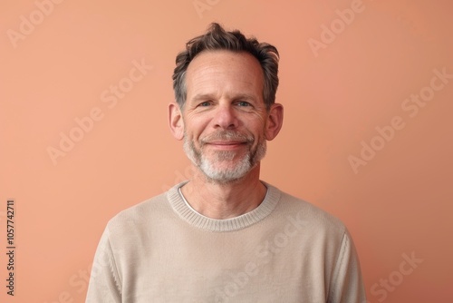 Warm Portrait of Smiling Middle-Aged Man on Soft Pastel Peach Background for Welcoming Design