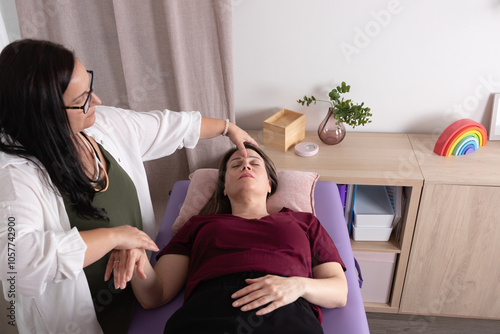 View from above of a woman lying on a stretcher with her psychotherapist in an acupressure session. Concept of therapy, wellness, psychotherapy, kinesiology and acupressure