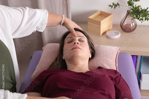 Obraz na plátně Close-up view from above of a woman receiving acupressure on her face