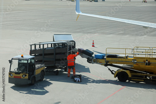 baggage handler wearing high visibility reflective suit unloading bags at the international airport photo