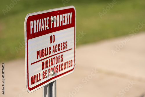 Rectangle image of a red and white PRIVATE PROPERTY, NO PUBLIC ACCESS, VIOLATORS WILL BE PROSECUTED sign  screwed to a metal post, side view with copy space