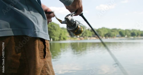 Closeup low shot of a man's hands reeling while fishing on the Catawba River near Charlotte, North Carolina. No audio.