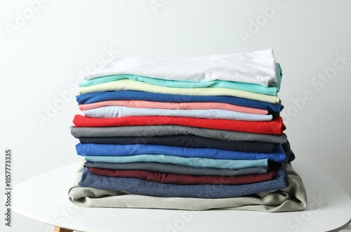 A stack of freshly washed, neatly folded clothing on a wooden table