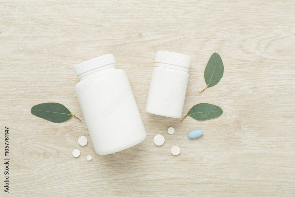 Bottles with pills and green leaves on wooden background, top view Bottles with pills and green leaves on wooden background, top view