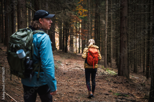 Hiking group of people in outdoor gear and sports clothing walking through dark forest