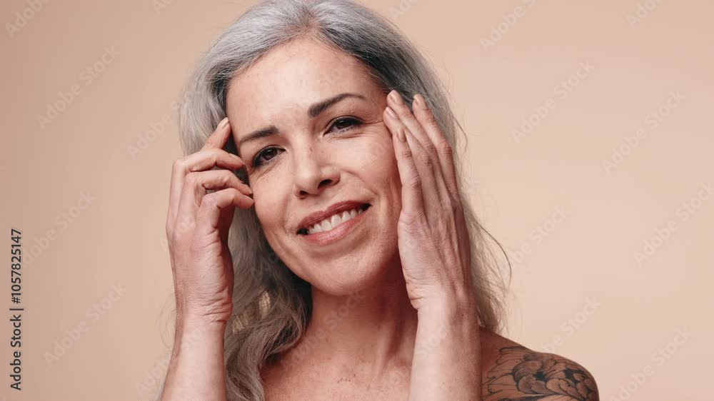 Portrait of a senior woman with silver hair, touching her face gently, showcasing radiant, healthy skin on a neutral background. Portrait of a senior woman with silver hair, touching her face gently, showcasing radiant, healthy skin on a neutral background.