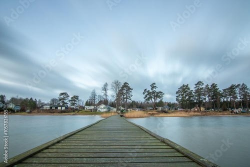 Sunrise over a lake in autumn. A wooden jetty protrudes into the water while grass has established itself on the sandy beach. The lake and beach, located on Lake Vänern in Näs Sannar, Sweden, Scandina photo