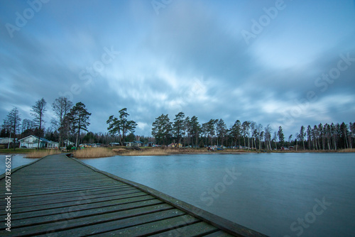 Sunrise over a lake in autumn. A wooden jetty protrudes into the water while grass has established itself on the sandy beach. The lake and beach, located on Lake Vänern in Näs Sannar, Sweden, Scandina photo