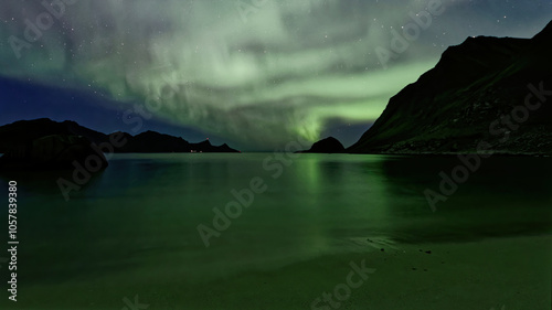 Aurora borealis/Northern Lights and its reflection on sandy seashore. Lofoten Islands, Northern Norway.