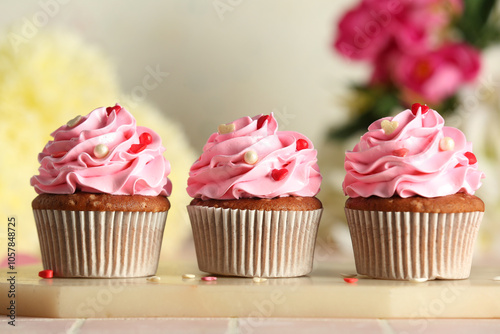 Board with tasty cupcakes for Valentine's Day on tile table