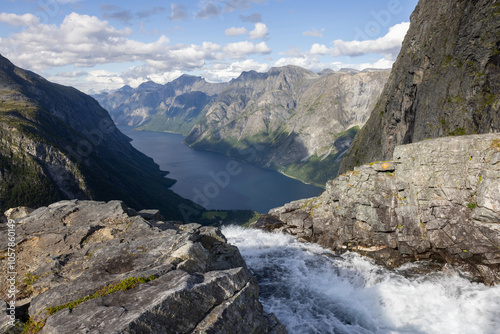 View of the landscape with the source of the Mardalsfossen waterfall in Norway. Grey sky with clouds, grey mossy rocks, white water of the waterfall and dark blue Eikesdalsvatnet lake photo