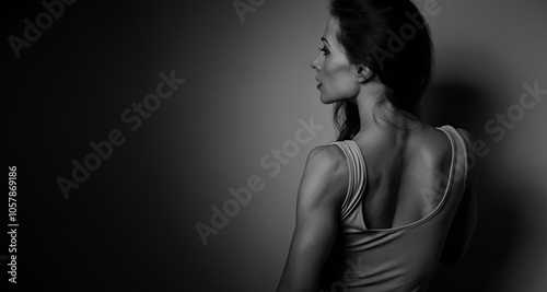 Gymnastics slim woman with long hair, sport strong body, with half shadow and light on studio background. Closeup with empty copy space. Art. Profile back view portrait. photo