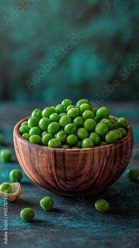 Freshly harvested green peas arranged neatly in a wooden bowl on a textured s...