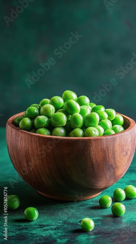 Freshly harvested green peas arranged neatly in a wooden bowl on a textured s...