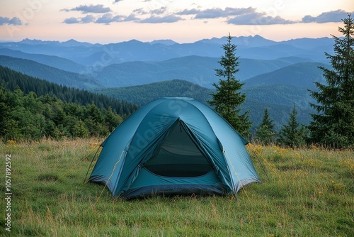 A tent set up on a grassy hilltop with stunning sunset views over mountains