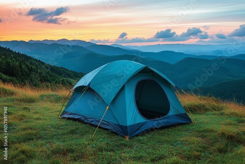 A tent set up on a grassy hilltop with stunning sunset views over mountains