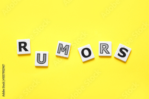 Word RUMORS on yellow background. Gossip concept photo