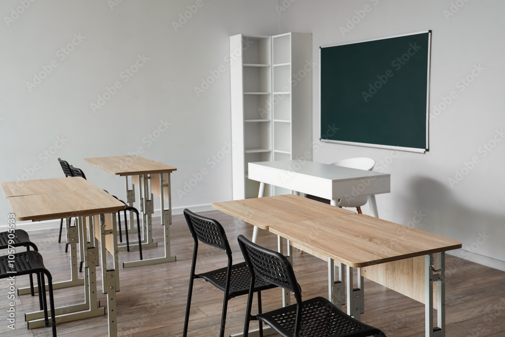 Interior of empty classroom with school desks and clean chalkboard