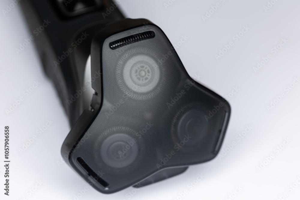 Beard shaver on a white background. Cutting blades protected by plastic cover. Photo taken in artificial light with clearly visible details of the shaver
