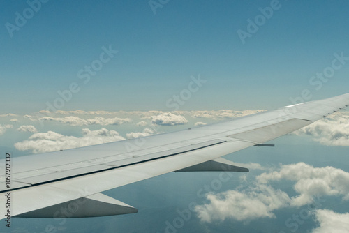 Looking out an airplane window at clouds under the wing of my airplane.   
 photo