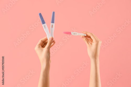 Female hands with pregnancy tests on pink background. Closeup