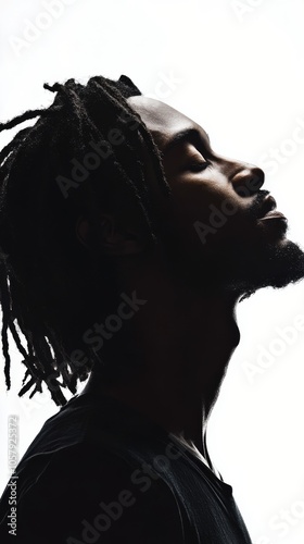 Profile of a man with dreadlocks against a bright background showcasing stron...